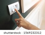 Small photo of Closeup of Asian female right hand is turning on or off on grey light switch over green wall. Copy space.