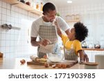 African family cooking baking cake or cookie in the kitchen together, Happy smiling Black son enjoy playing and touching his father nose with finger and flour while doing bakery at home. BeH3althy