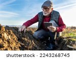 Small photo of Mature farmer checking clod of earth in field in autumn time