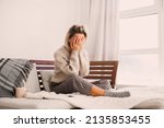 Small photo of Frustrated nervous sad middle aged woman sitting on sofa, touching forehead, suffering from headache alone at home. Worried stressed adult female at home