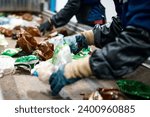 Worker sorts trash on conveyor belt at waste recycling plant