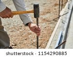 Small photo of Man using a sledge hammer to fasten in a cement form stake with shallow depth of field
