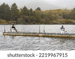 Small photo of Two men sitting on a dock on a fresh water lake fishing on a cold and deary day.
