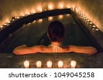 Spa luxury jacuzzi woman relaxing in whirlpool hot tub with water massaging jets. Woman in candlelight enjoying hydrotherapy in private massage pool. Hotel lifestyle.