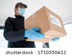 Home delivery shopping box man wearing gloves and protective mask delivering packages at door.