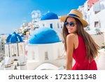 Europe Greece Santorini travel vacation woman on famous santorini Oia island travel destination. Happy young tourist girl in hat and sunglasses relaxing at blue dome church. Summer wanderlust.