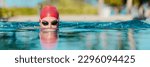 Small photo of Swimming athlete man creative portrait wearing swim goggles and swim cap in swimming pool while doing breast stroke. Male swimmer swimming breaststroke in pool outside. Panoramic banner.