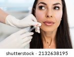 Small photo of Attractive woman is getting a rejuvenating facial injections at beauty clinic. The expert beautician is filling female wrinkles with botulinum toxin injections or hyaluronic acid fillers.