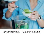 Close up woman adding wheat grass green powder during making smoothie on the kitchen. Superfood supplement. Healthy detox vegan diet. Healthy dieting eating, weight loss program. Selective focus.
