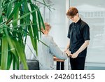 Small photo of Friendly smiling young male waiter serves a client in cafe. Affable restaurant worker brings coffee drink. Man in cafeteria communicates with visitor accepts order. Student working part-time in cafe.