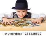 Happy boy in black hat with money on the table, isolated on white
