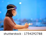 Small photo of Asian woman in face shield,medical face mask outbreak,. Having absent-mindedness or depression that results from status pandemic risk Corona virus disease COVID-19 infection. Concept new normal.