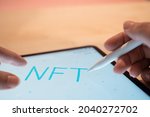 NFT Non-interchangeable token creation of crypto art, concept. NFT inscription on the tablet screen, hands write with a stylus in a graphic editor, digital art concept