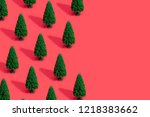 Minimal composition pattern background of green Christmas trees on pastel red. New Year concept.