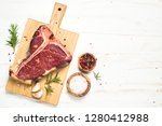 T-bone beef steak on white wooden table with spices. Ready for cooking. Top view with copy space.
