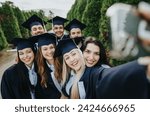 Small photo of Proud graduates in park wearing caps and gowns, create memories while celebrating their bachelor’s degrees. Faculty faculty colleagues and friends take a group selfie.