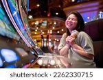 Small photo of exited asia female woman slot machine gambling cheerful smile hand pressing bet button in casino club entertainment concept,exited asian woman hand play slot machine in casino hotel