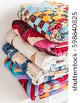 Small photo of magnificent colored patchwork quilt put by a pile on a white table close up. a concept with colorful scrappy blankets.